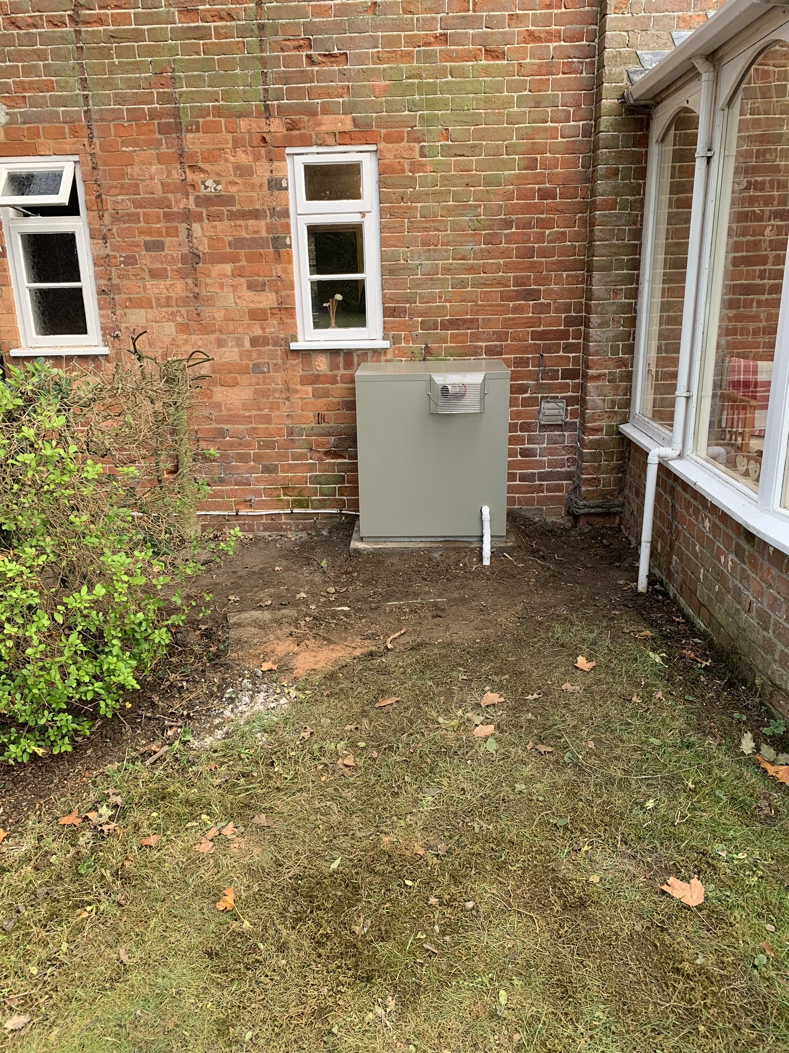 Outdoor oil boiler against a red brick wall in a garden